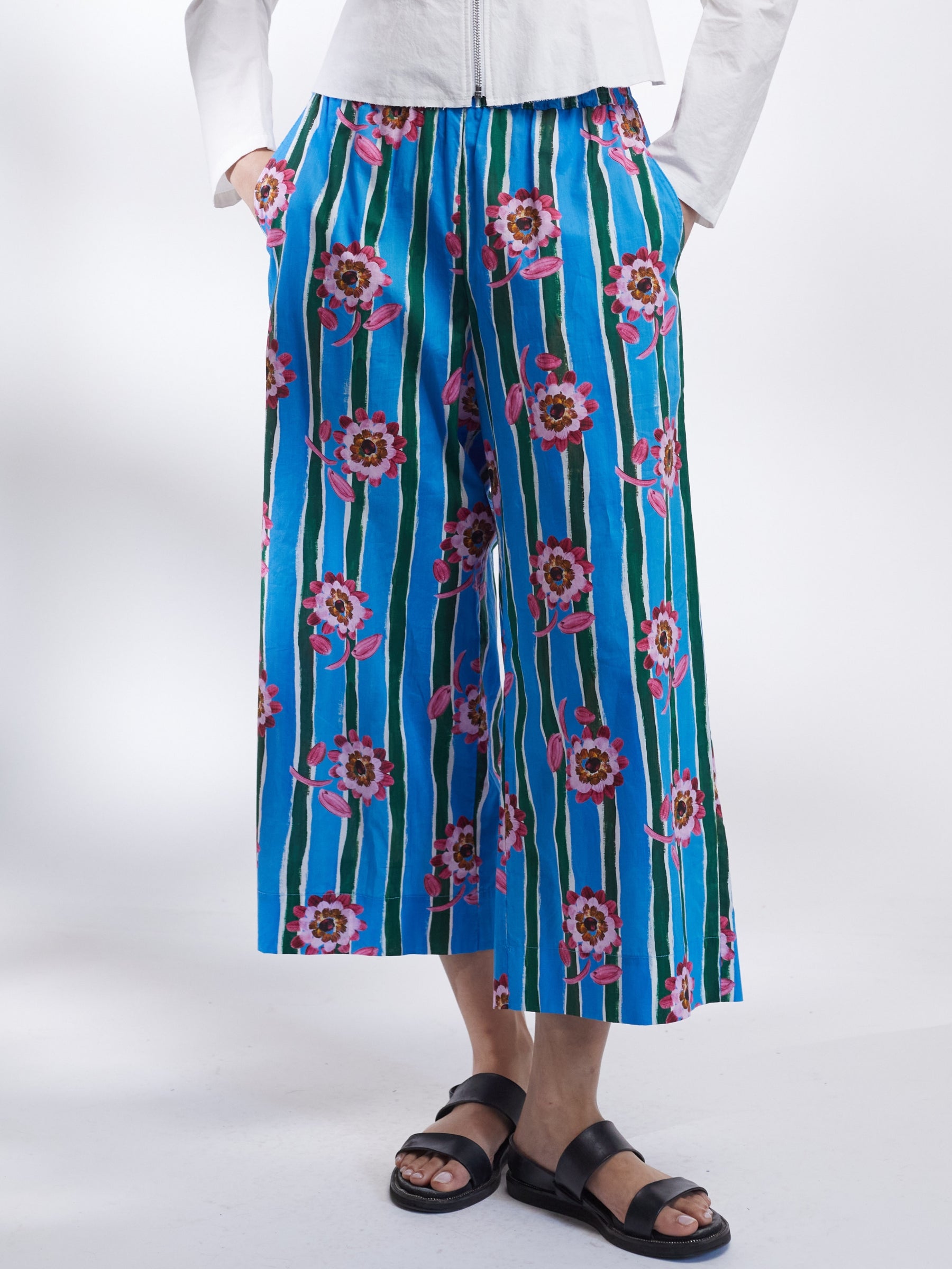 Woman wearing a white jacket and blue floral pants on a white background _ Made in England | Justine Tabak