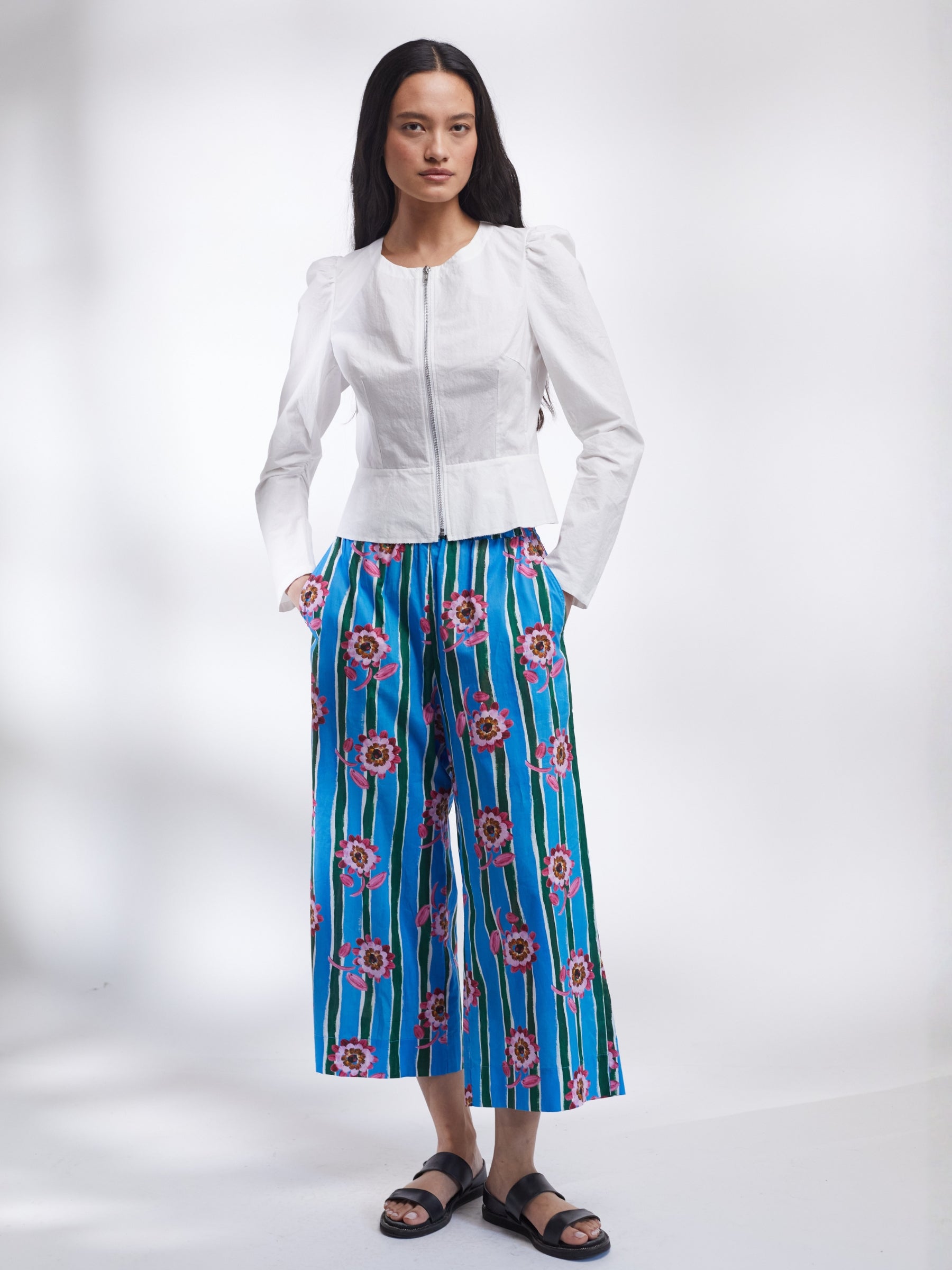Woman wearing a white jacket and blue floral pants on a white background _ Made in England | Justine Tabak