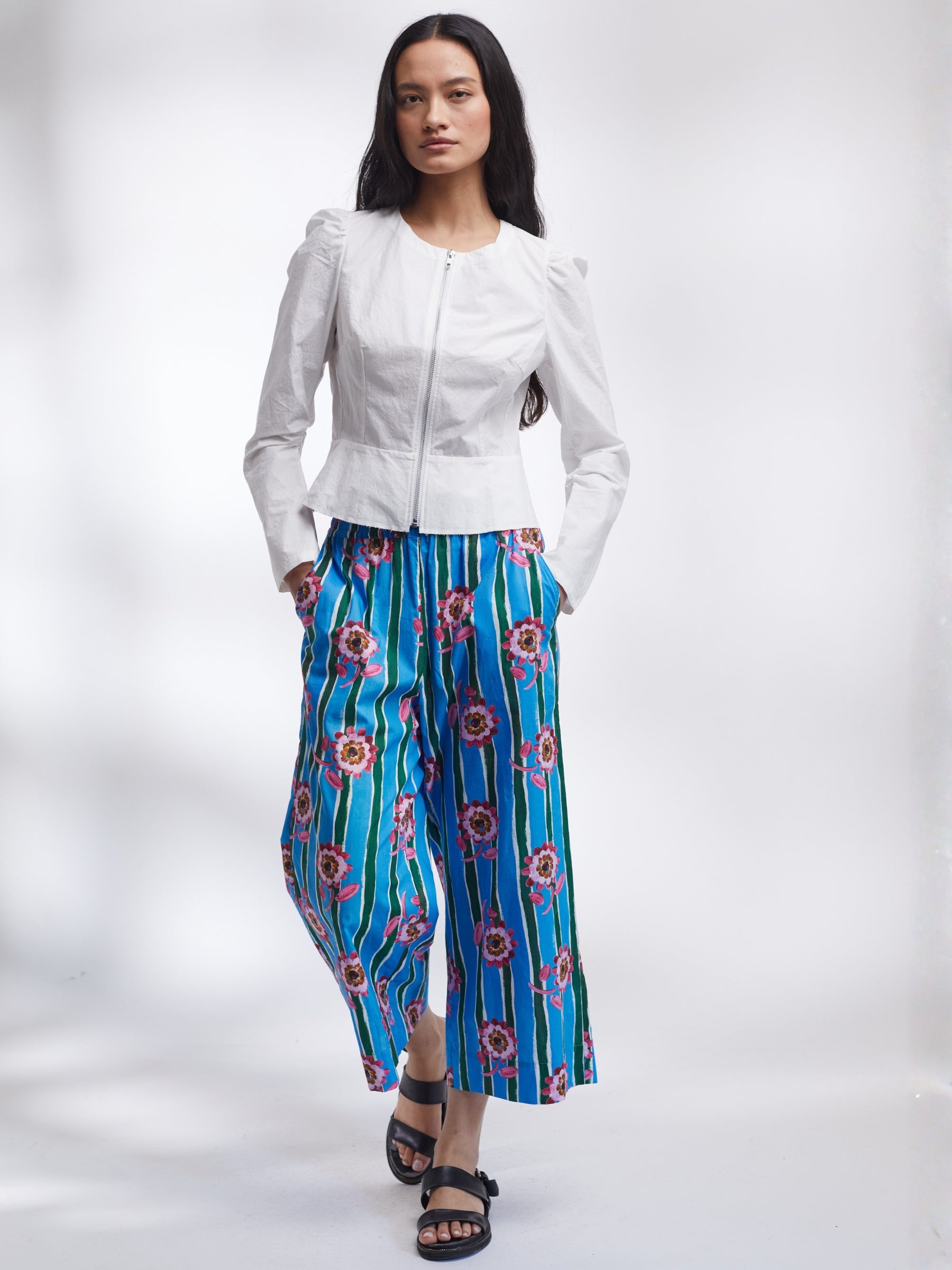 Woman wearing a white jacket and blue floral pants on a white background _ Made in England | Justine Tabak