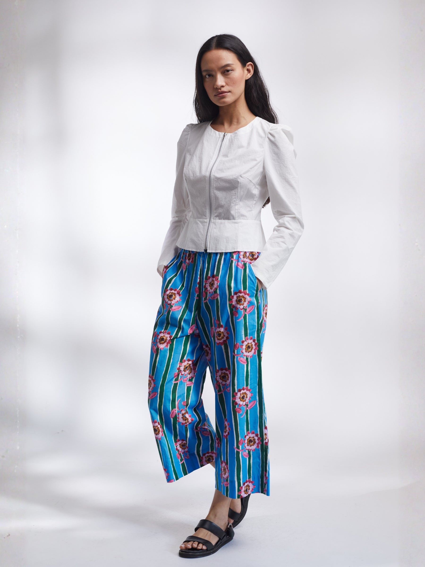 Woman wearing a white jacket and blue floral pants on a white background _ Made in England | Justine Tabak