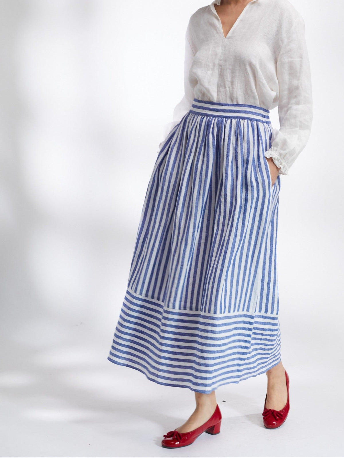 Woman wearing a white shirt and blue striped skirt on a white background